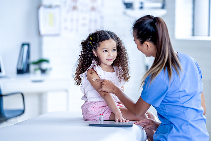 Little girl getting a vaccine from a female doctor.